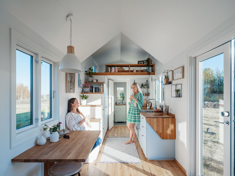 Two ladies chatting in a Norwegian tiny house kitchen and dining area.