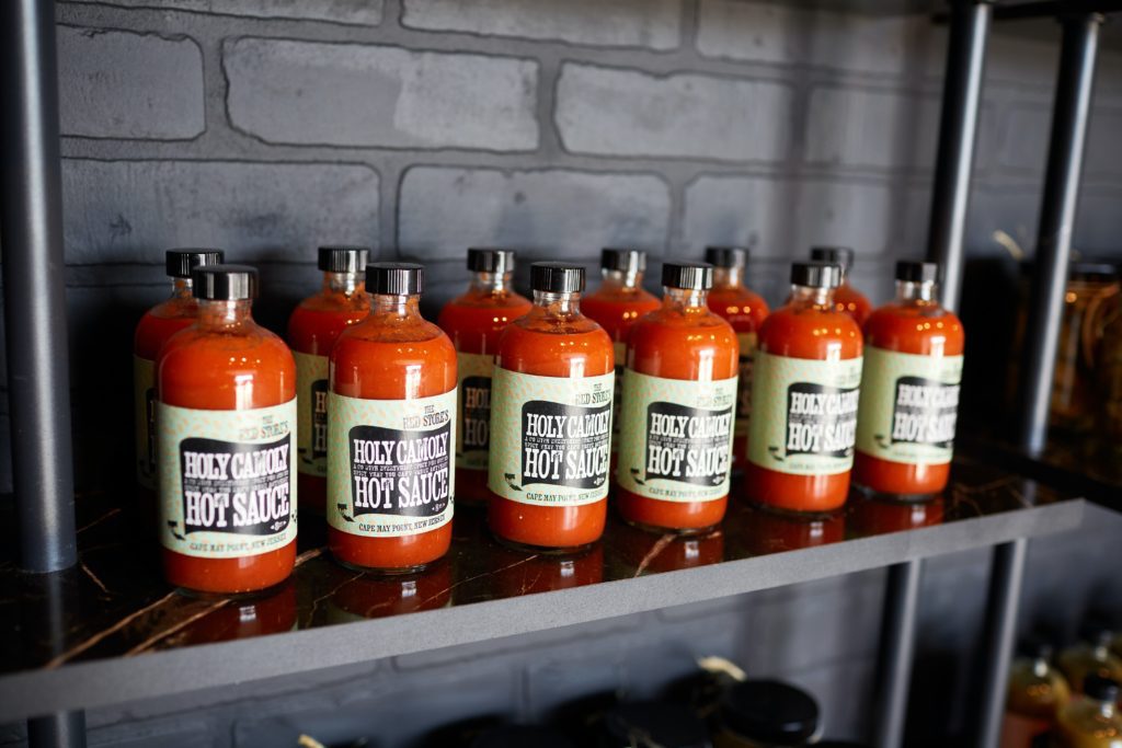 A shelf stocked with hot sauce called "Holy Camoly hot sauce"